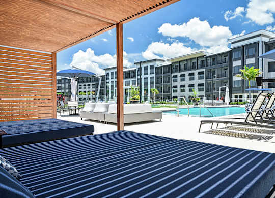 A pool area with sun loungers and a building in the background at Ironwood Flats Apartments, Brandon, Florida