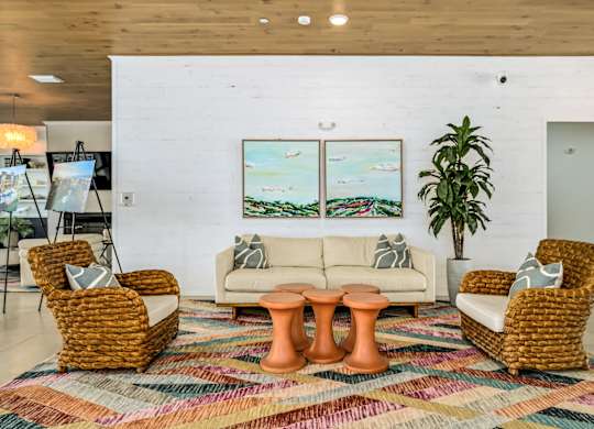 A living room with a white couch, two wicker chairs, and a colorful rug at Ironwood Flats Apartments, Brandon, FL