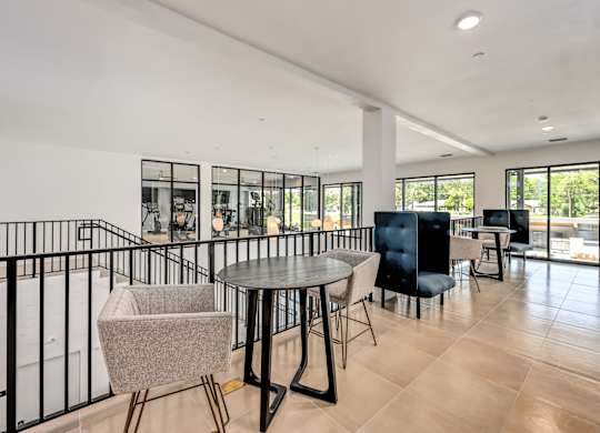 A modern living room with a black railing and a round table with chairs at Ironwood Flats Apartments, Brandon, FL, 33511