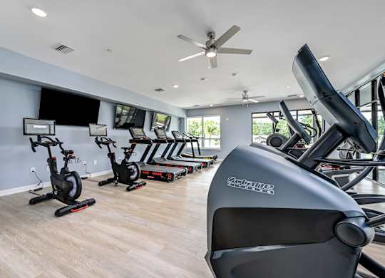 A gym with a variety of exercise equipment including stationary bikes and rowing machines. at Ironwood Flats Apartments, Brandon, Florida