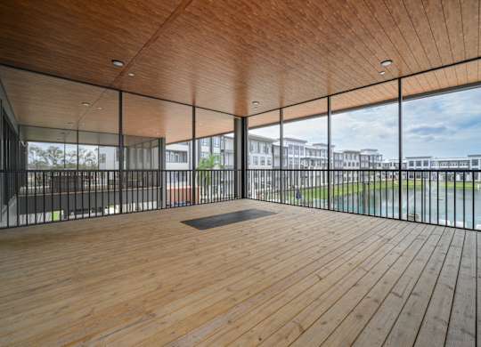 A room with wooden floors and a glass wall overlooking a grassy area.