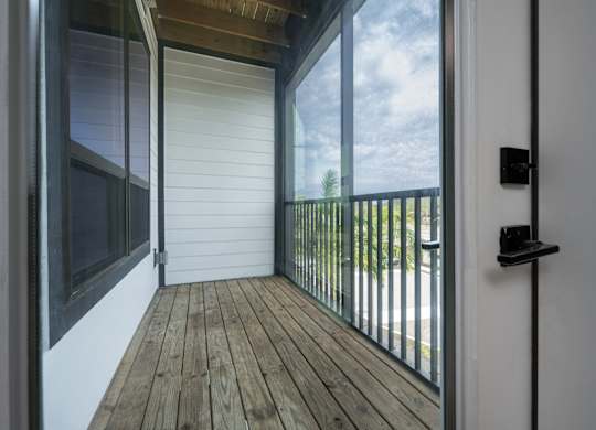 A balcony with a sliding door and a black railing.