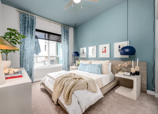 a bedroom with blue walls and a large window with blue curtains at Ironwood Flats, Brandon, Florida
