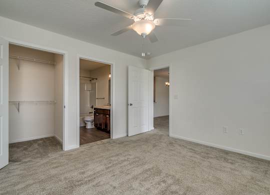 A room with a ceiling fan and carpeted floor.