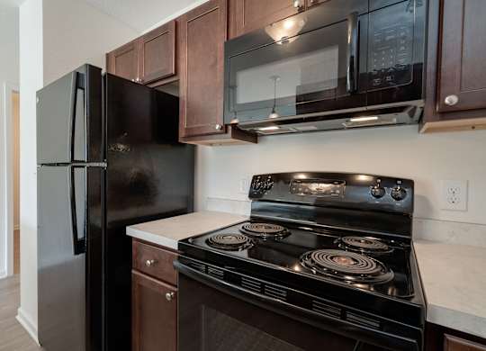 A black refrigerator and stove in a kitchen.