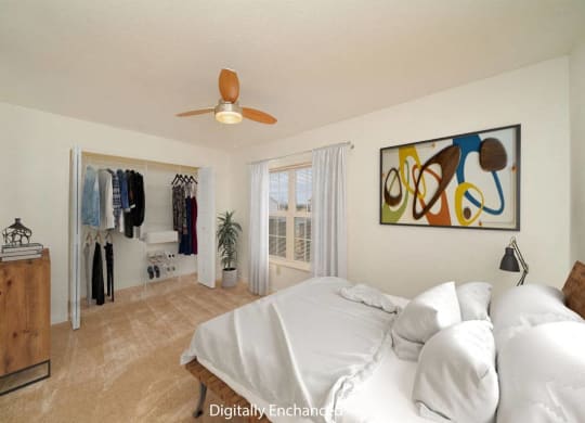 a bedroom with a bed, a ceiling fan and a closet with organizers at Limestone Creek Apartment Homes, Madison, AL