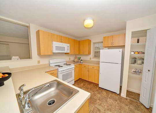 a kitchen with white appliances and wooden cabinets at Limestone Creek Apartment Homes, Madison, AL