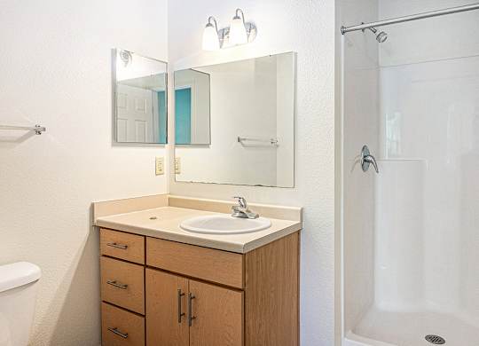 A bathroom with a sink, mirror, and shower at Limestone Creek Apartment Homes, Madison, AL