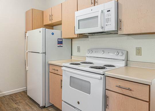 A kitchen with a white refrigerator, stove, and microwave at Limestone Creek Apartment Homes, Madison, AL
