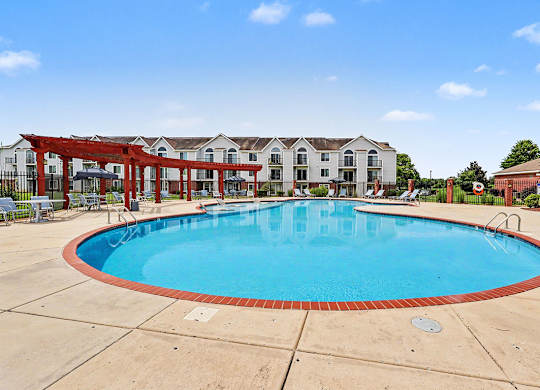 A large swimming pool in front of a building with a red pergola at Limestone Creek Apartment Homes, 35756
