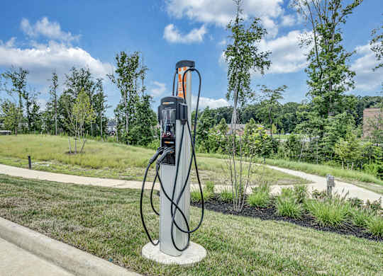 An electric vehicle charging station is on a concrete pad in a grassy area at Luxe 360 Apartment Complex in Midlothian Virginia