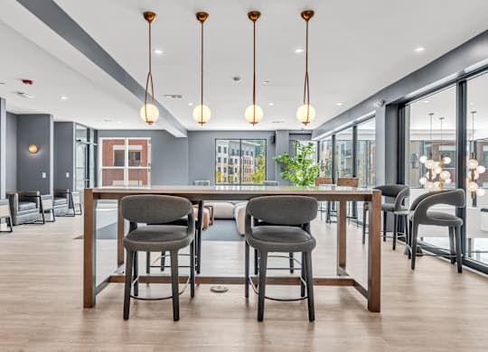 A modern dining area with a long table and chairs at Luxe 360 on Centerpointe Apartments, Midlothian, Virginia