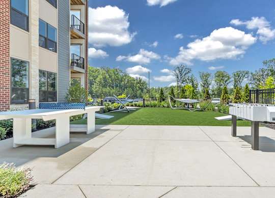 A sunny day at a residential complex with a white bench and a concrete path at Luxe 360 on Centerpointe Apartments, Midlothian, 23114