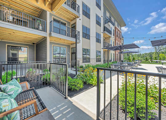 A balcony with a table and chairs overlooks a courtyard at Luxe 360 on Centerpointe Apartments, Midlothian, VA, 23114