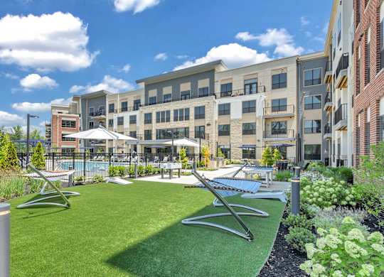 A sunny day at a modern apartment complex with a green lawn and a pool at Luxe 360 on Centerpointe Apartments, Virginia