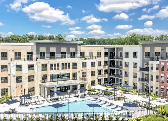 A large apartment complex with a pool in the middle at Luxe 360 on Centerpointe Apartments, Midlothian, VA