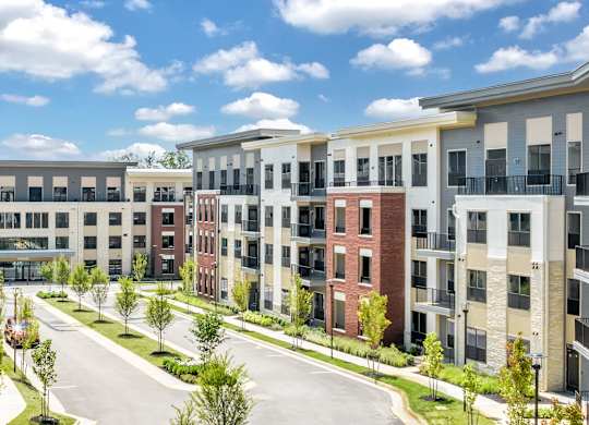 A row of modern apartment buildings with balconies and trees in front at Luxe 360 on Centerpointe Apartments, Virginia