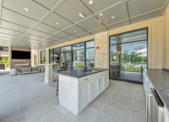 A modern kitchen with a large island and a view of the backyard at Luxe 360 on Centerpointe Apartments, Virginia, 23114