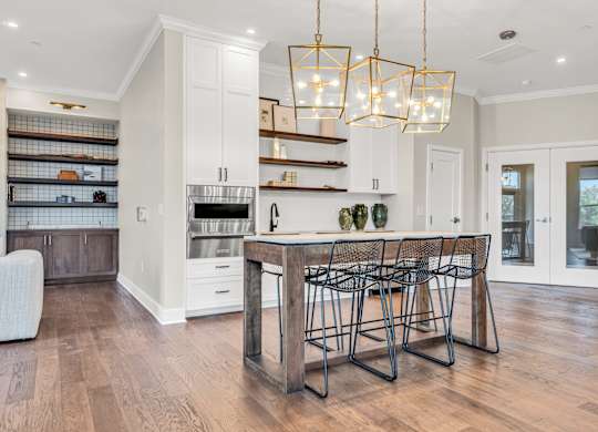 A kitchen with a wooden table and chairs and a hanging light fixture at Luxe 360 on Centerpointe Apartments, Midlothian