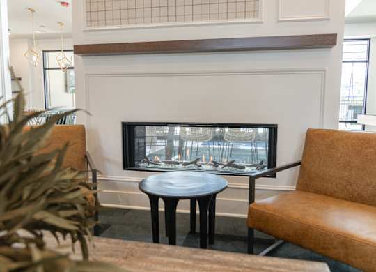 A living room with a fireplace and a brown leather chair at Luxe 360 on Centerpointe Apartments, Virginia