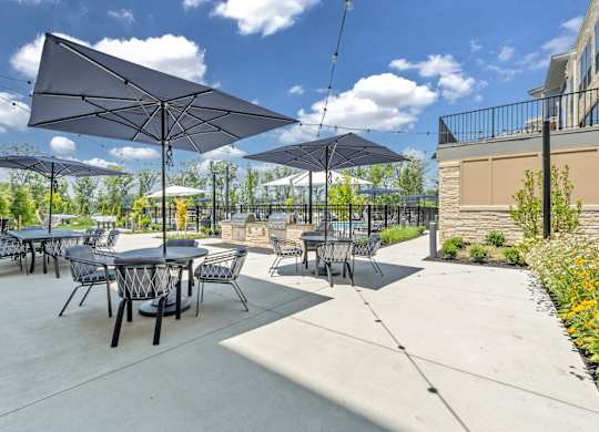 A patio with tables and chairs under umbrellas at Luxe 360 on Centerpointe Apartments, Midlothian, VA