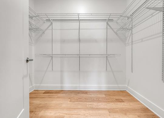 Empty walk-in closet with shelves and a wooden floor at Luxe 360 on Centerpointe Apartments, Midlothian, Virginia