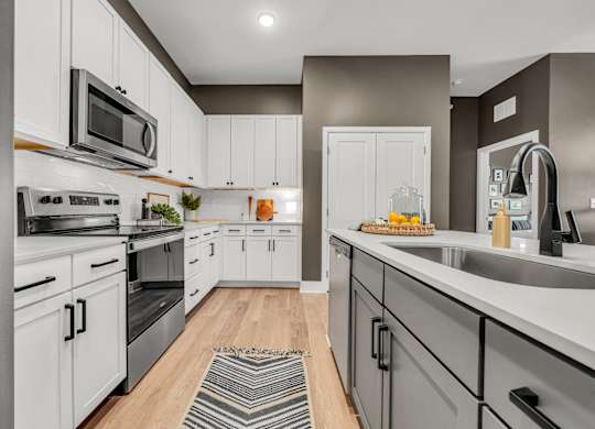 A modern kitchen with white cabinets and stainless steel appliances at Luxe 360 on Centerpointe Apartments, Midlothian, Virginia