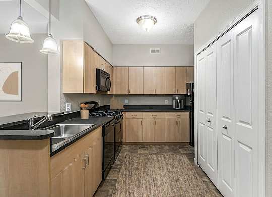 A kitchen with wooden cabinets and black countertops at Lynbrook Apartments and Townhomes, Elkhorn, NE, 68022