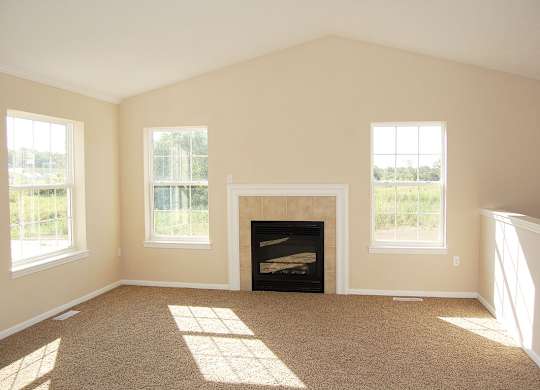 A living room with a fireplace and windows at Lynbrook Apartment Homes and Townhomes, Elkhorn