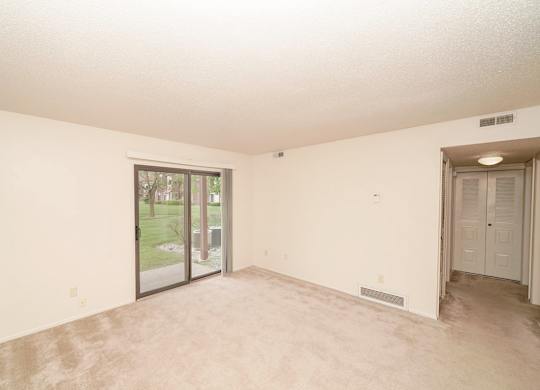 A  living room with a sliding glass door leading to a patio at Madeira Apartments in Kalamazoo, MI