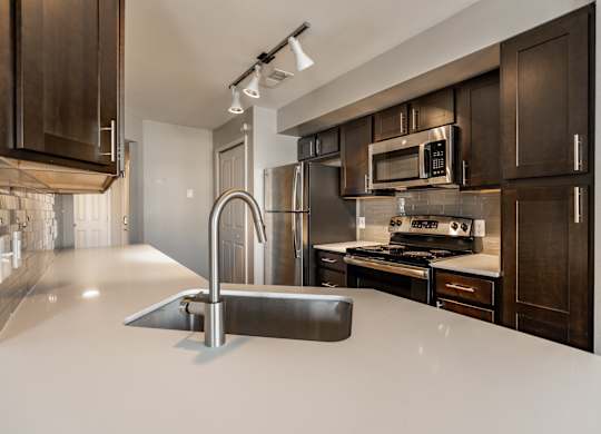 A modern kitchen with dark brown cabinets and a white countertop at Mallard Bay Apartments, Crown Point, Indiana