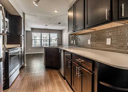A modern kitchen with dark wood cabinets and stainless steel appliances at Mallard Bay Apartments, Crown Point, Indiana