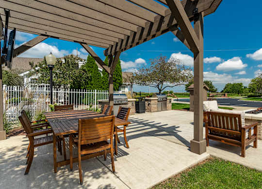 A wooden patio with a table and chairs under a pergola at Mallard Bay Apartments, Crown Point, Indiana
