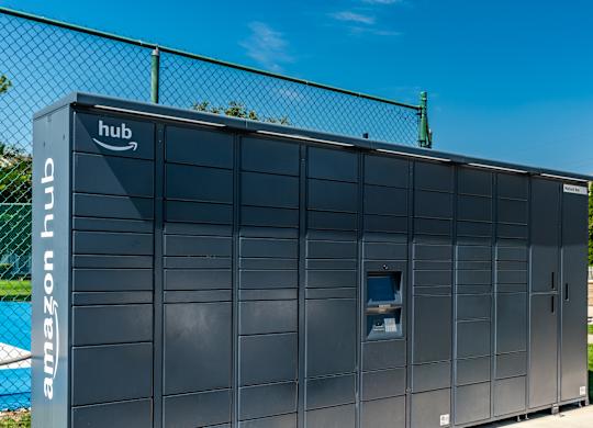 A large Amazon hub building is shown with a fence in the background at Mallard Bay Apartments, Crown Point, Indiana
