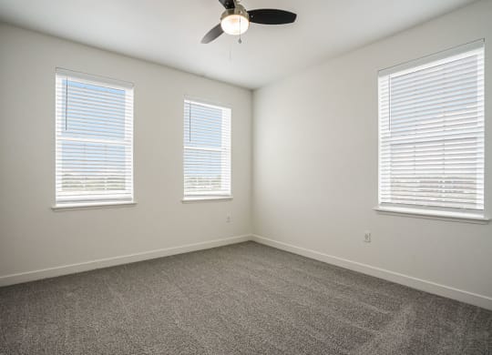 a bedroom with three windows and a ceiling fan at Meadowbrooke Apartment Homes, Grand Rapids, Michigan