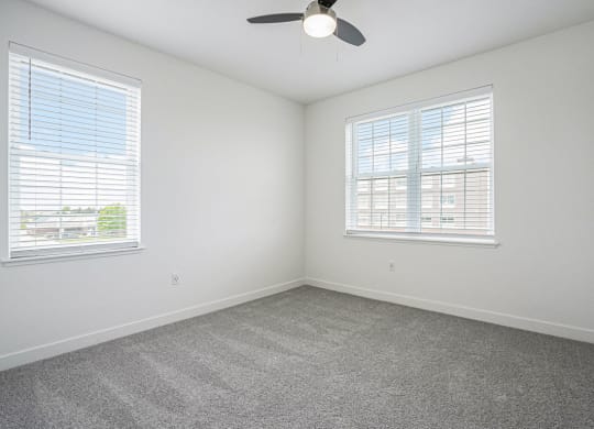 a bedroom with two windows and a ceiling fan at Meadowbrooke Apartment Homes, Michigan