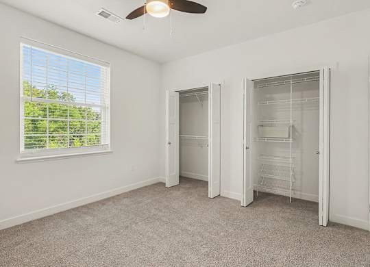 A bedroom with a ceiling fan and a window with blinds at Meadowbrooke Apartment Homes in Grand Rapids, MI 49512