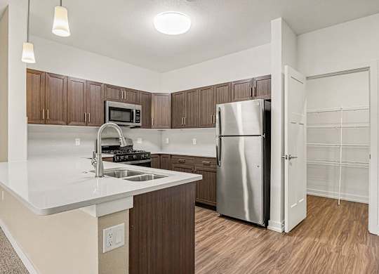 A kitchen with a breakfast bar and a stainless steel refrigerator at Meadowbrooke Apartment Homes in Grand Rapids, MI 49512