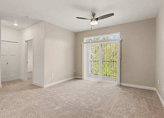 A living room with a ceiling fan and carpeted floor at Meadowbrooke Apartment Homes in Grand Rapids, MI 49512