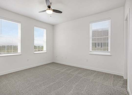 A bedroom with a ceiling fan and three windows at Meadowbrooke Apartment Homes in Kentwood, MI 49512