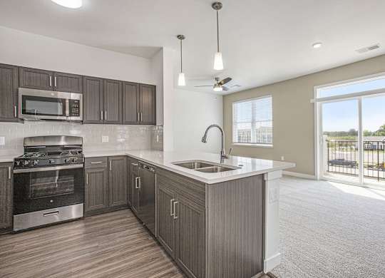 A modern kitchen with dark wood cabinets and stainless steel appliances at Meadowbrooke Apartment Homes in Kentwood, MI 49512