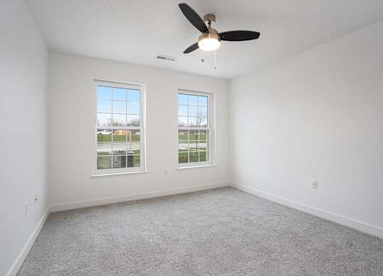 A bedroom with a ceiling fan and two windows at Meadowbrooke Apartment Homes in Kentwood, MI 49512