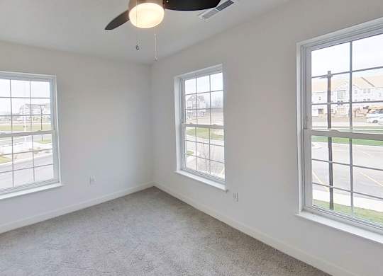 A bedroom with a ceiling fan and three windows at Meadowbrooke Apartment Homes in Kentwood, MI 49512