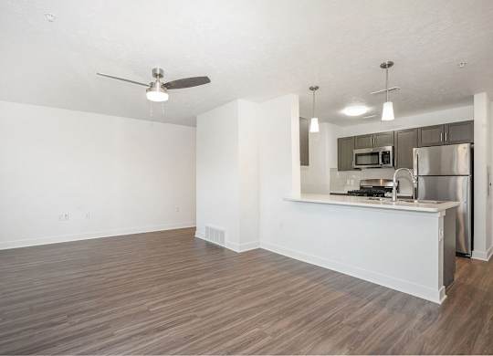 A living room leading to a kitchen with a breakfast bar at Meadowbrooke Apartment Homes in Kentwood, MI 49512