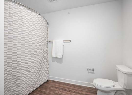 A bathroom with a toilet and a shower curtain at Meadowbrooke Apartment Homes in Kentwood, MI 49512