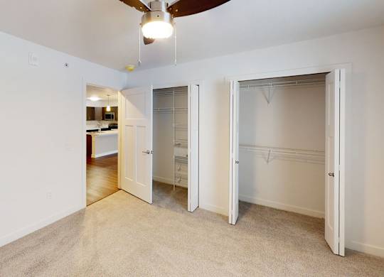 A bedroom with a ceiling fan and two large closets at Meadowbrooke Apartment Homes in Kentwood, MI 49512