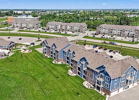 A large grassy area with a swimming pool and apartment buildings at Meadowbrooke Apartment Homes in Grand Rapids, MI 49512