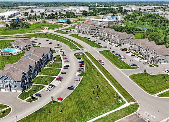 A large grassy area with a road and apartment buildings at Meadowbrooke Apartment Homes in Grand Rapids, MI 49512