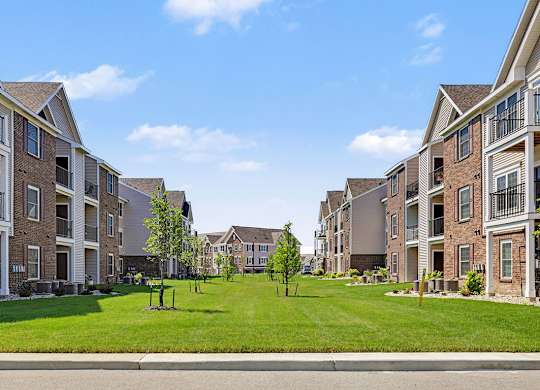A grassy courtyard between modern apartment buildings at Meadowbrooke Apartment Homes in Grand Rapids, MI 49512