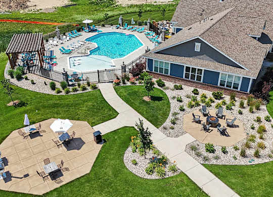 A pool and a patio area with grills, a fire pit, and seating areas at Meadowbrooke Apartment Homes in Grand Rapids, MI 49512